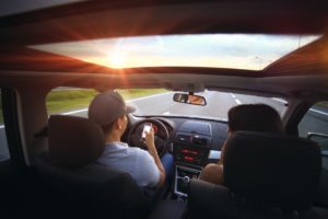 man driving looking at phone